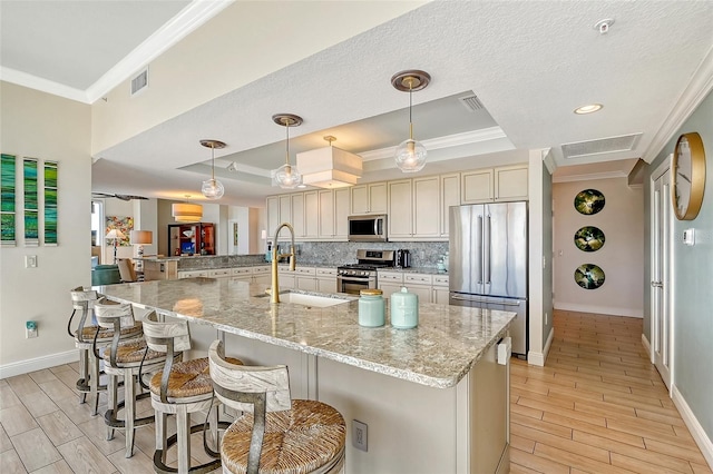 kitchen with tasteful backsplash, stainless steel appliances, ornamental molding, light stone counters, and a raised ceiling