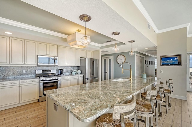 kitchen with appliances with stainless steel finishes, sink, hanging light fixtures, light stone counters, and a spacious island