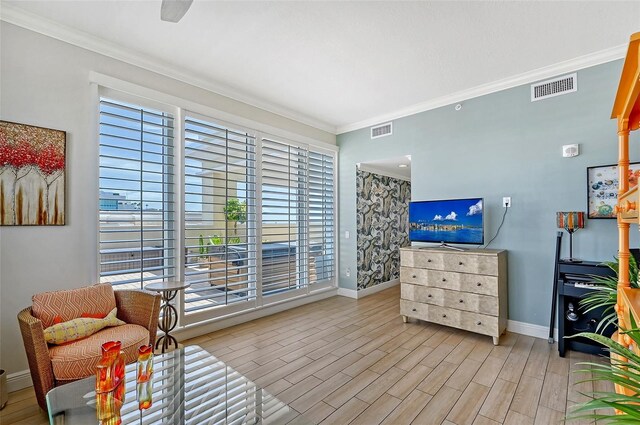 sitting room with light hardwood / wood-style floors, crown molding, and a healthy amount of sunlight