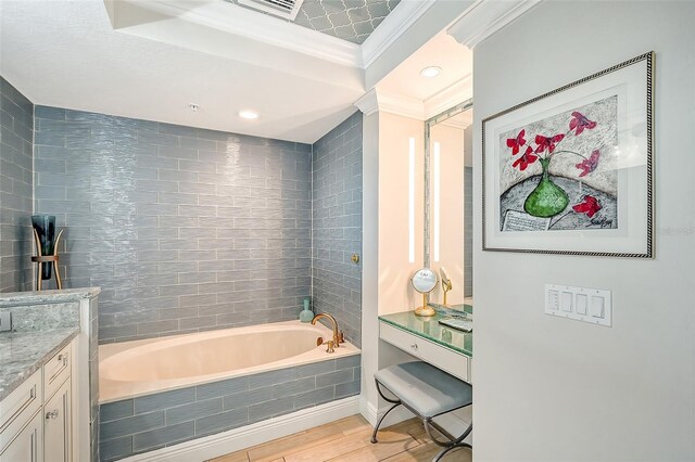 bathroom with a relaxing tiled tub, vanity, and ornamental molding