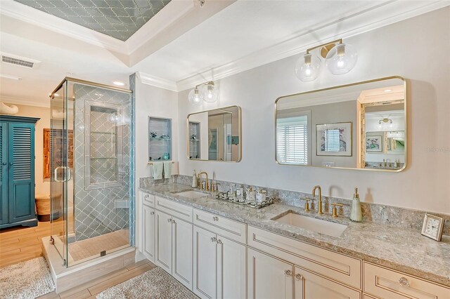 bathroom with double vanity, walk in shower, wood-type flooring, and ornamental molding