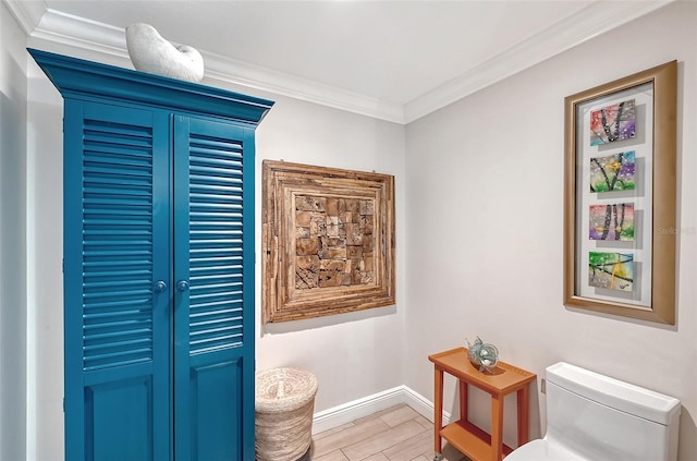 bathroom featuring hardwood / wood-style floors, crown molding, and toilet