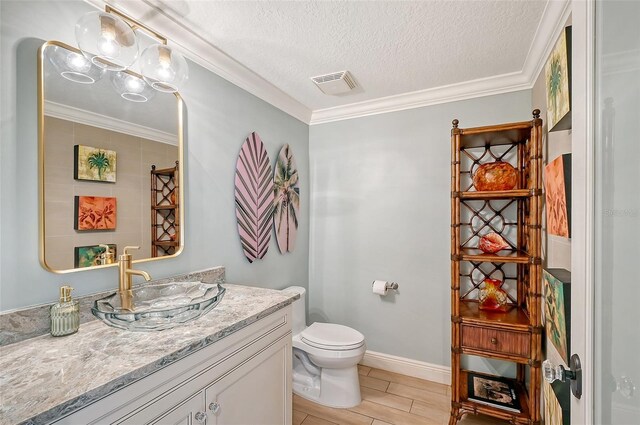 bathroom with tile patterned flooring, crown molding, a textured ceiling, toilet, and vanity