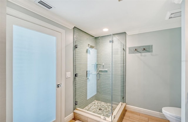 bathroom with a shower with shower door, ornamental molding, and toilet