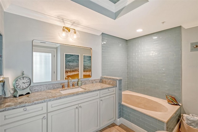 bathroom with ornamental molding, tiled bath, and vanity