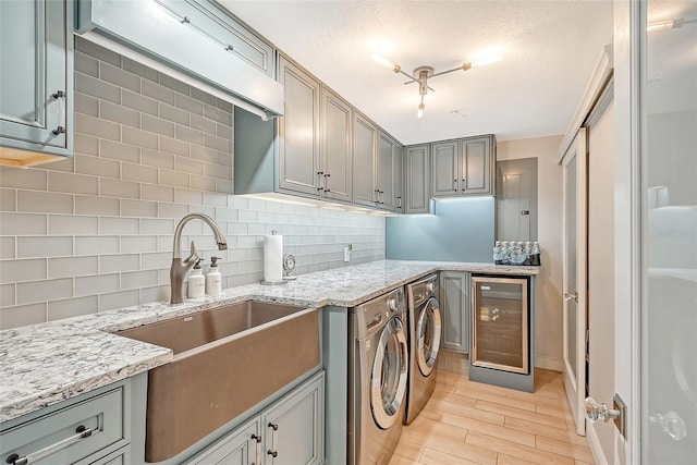 kitchen with wine cooler, sink, independent washer and dryer, light stone countertops, and decorative backsplash