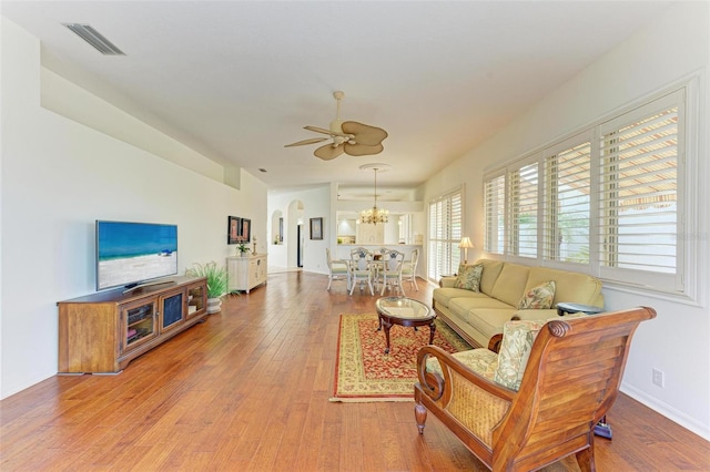 living room featuring ceiling fan with notable chandelier and wood-type flooring