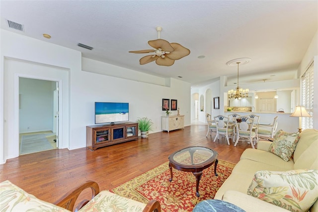 living room with ceiling fan with notable chandelier and hardwood / wood-style floors