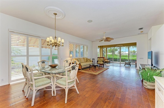 dining space with a wealth of natural light, hardwood / wood-style flooring, and ceiling fan with notable chandelier