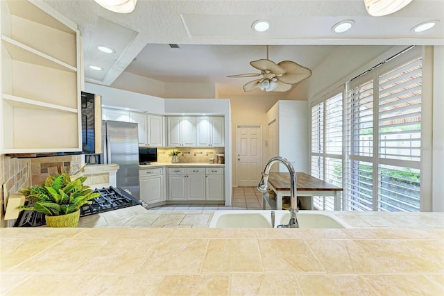 kitchen with high end fridge, ceiling fan, sink, light tile patterned floors, and backsplash