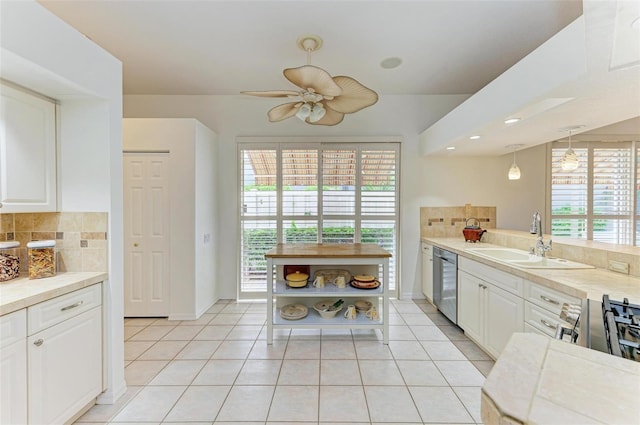 kitchen with white cabinets, stainless steel dishwasher, decorative backsplash, decorative light fixtures, and sink