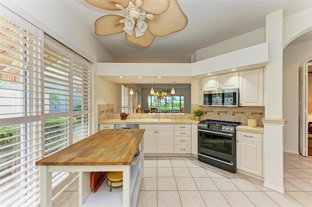 kitchen featuring appliances with stainless steel finishes, kitchen peninsula, backsplash, and light tile patterned floors