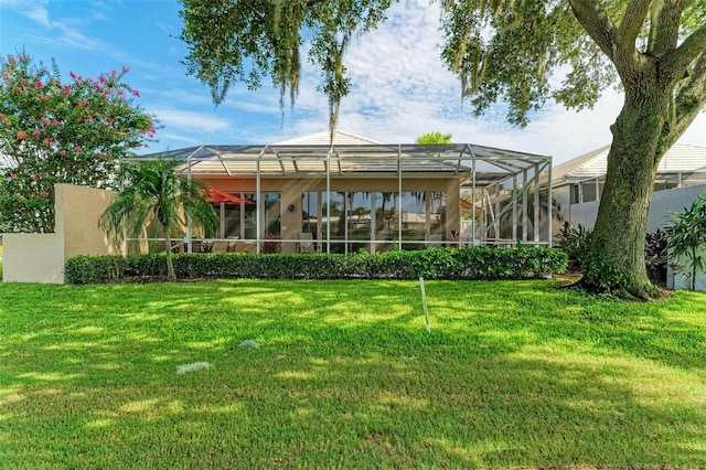 back of property featuring a lawn and glass enclosure