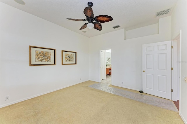 unfurnished bedroom with ensuite bath, light colored carpet, and ceiling fan