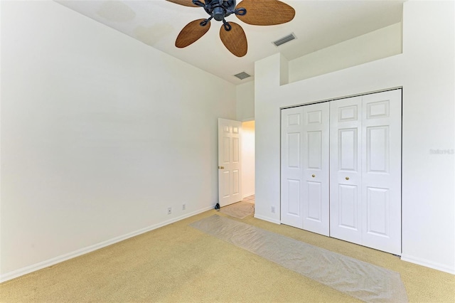 unfurnished bedroom with a closet, light colored carpet, and ceiling fan