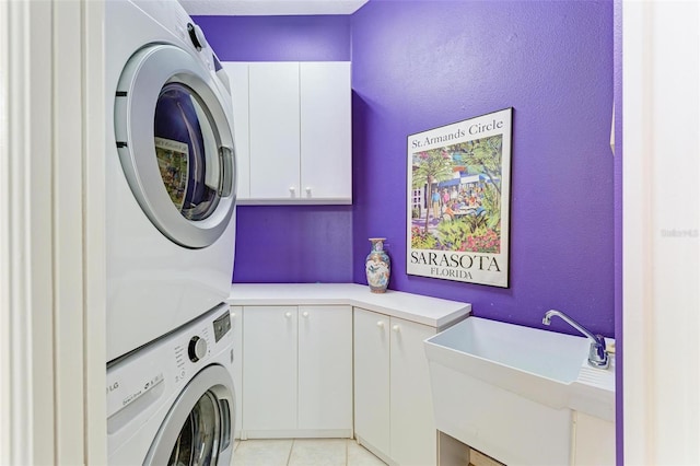 washroom featuring stacked washer / dryer, sink, cabinets, and light tile patterned floors