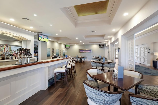 dining room featuring crown molding, dark hardwood / wood-style floors, a raised ceiling, and bar