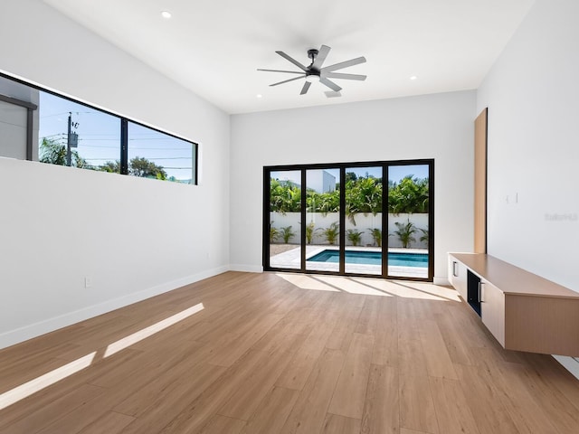 unfurnished living room with light wood-type flooring, a wealth of natural light, and ceiling fan