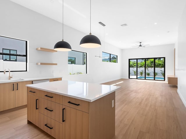 kitchen featuring light wood-type flooring, sink, decorative light fixtures, and a center island