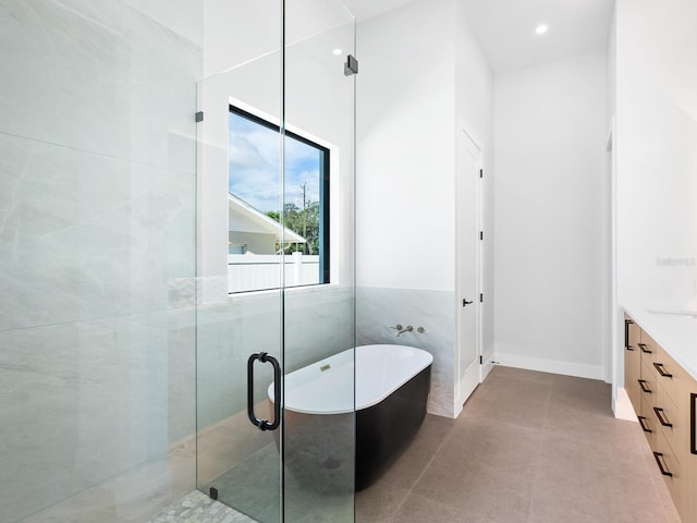 bathroom with separate shower and tub, tile patterned floors, vanity, and tile walls