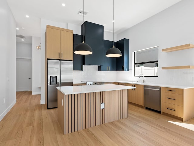 kitchen with a kitchen island, light hardwood / wood-style floors, decorative light fixtures, and stainless steel appliances