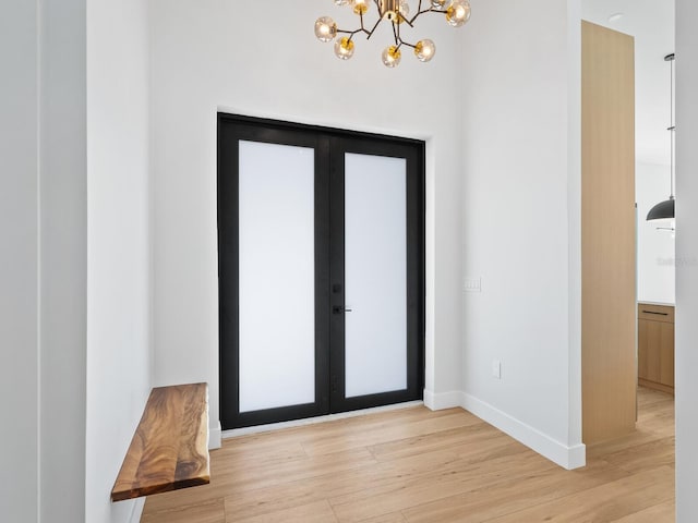 entryway featuring light wood-type flooring, french doors, and a chandelier