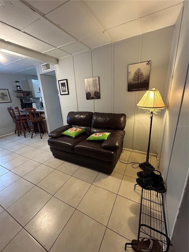 living room with a paneled ceiling and light tile patterned flooring