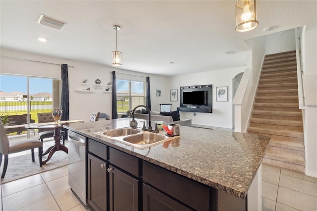 kitchen featuring sink, a kitchen island with sink, light stone counters, and decorative light fixtures