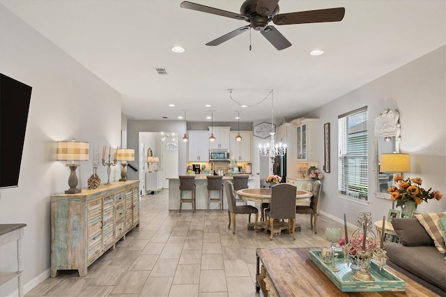 dining space with ceiling fan with notable chandelier