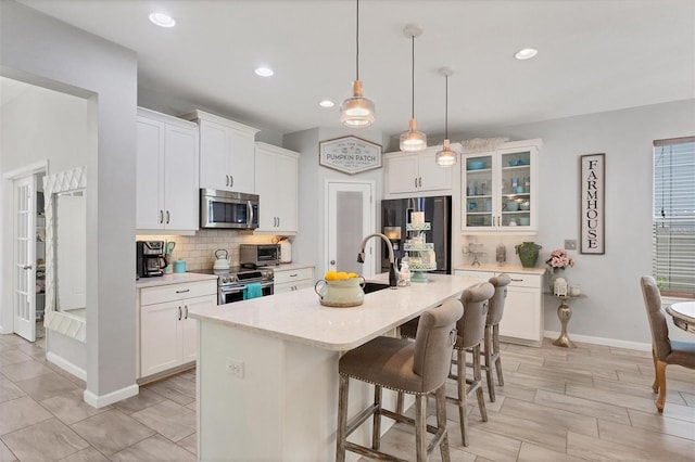 kitchen with white cabinetry, stainless steel appliances, and a kitchen island with sink