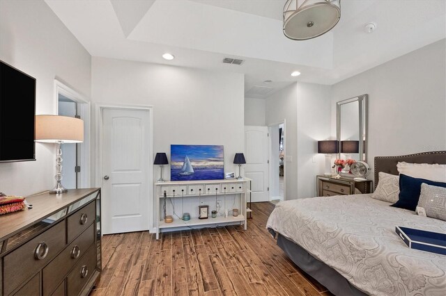 bedroom featuring light wood-type flooring and a raised ceiling