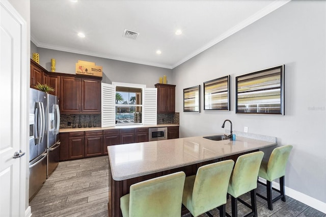 kitchen with kitchen peninsula, a breakfast bar, light hardwood / wood-style floors, sink, and decorative backsplash