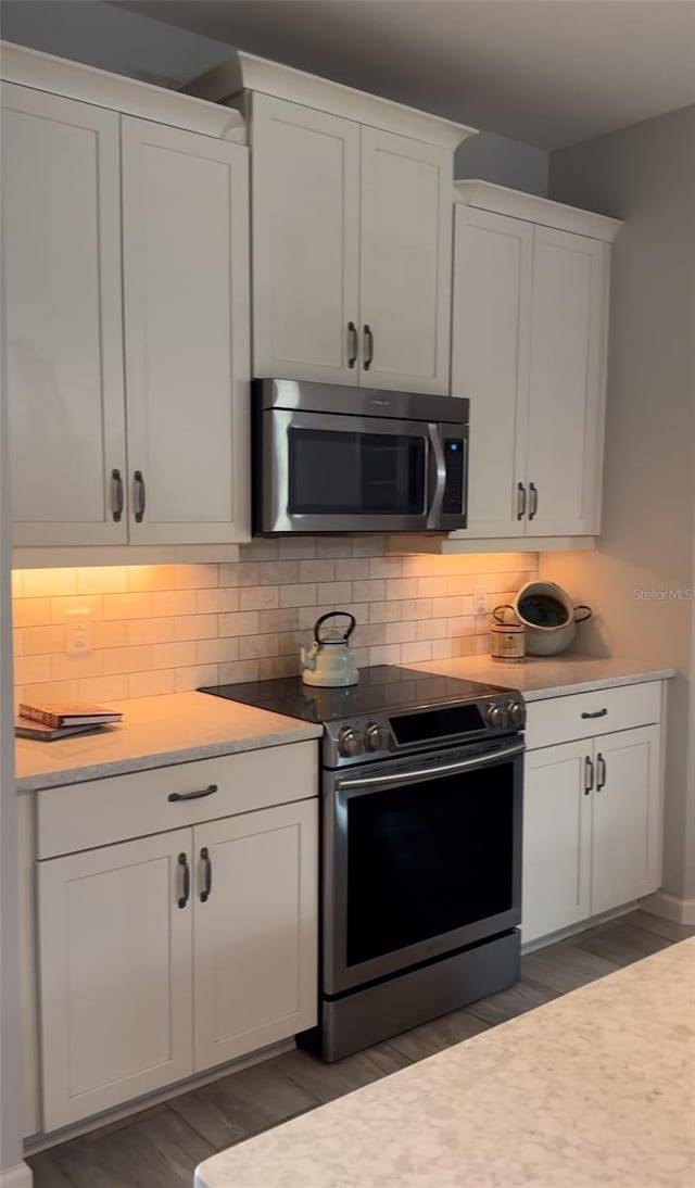 kitchen with dark hardwood / wood-style flooring, tasteful backsplash, stainless steel appliances, and white cabinets