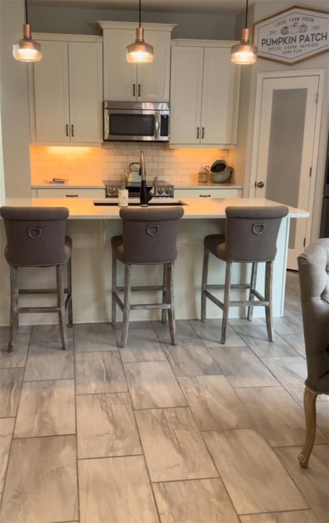 kitchen featuring a center island with sink, a kitchen breakfast bar, and decorative light fixtures