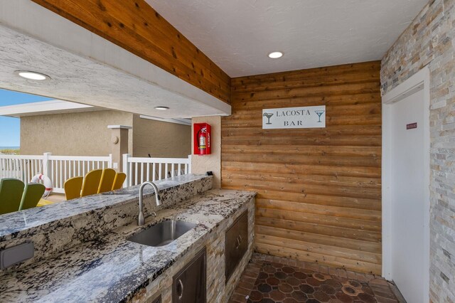 kitchen featuring a textured ceiling, light stone counters, and sink