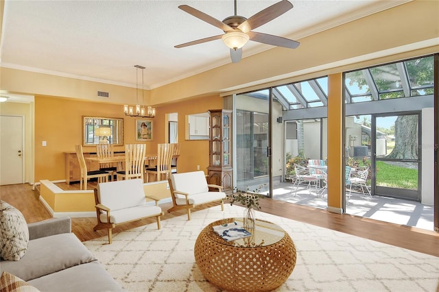 living room with ornamental molding, ceiling fan with notable chandelier, a textured ceiling, and light wood-type flooring