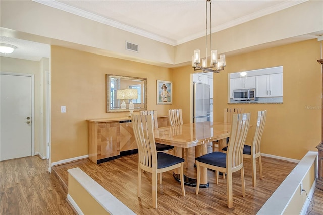 dining area with ornamental molding, light hardwood / wood-style floors, and a notable chandelier