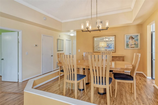 dining space with wood-type flooring, ornamental molding, and a chandelier