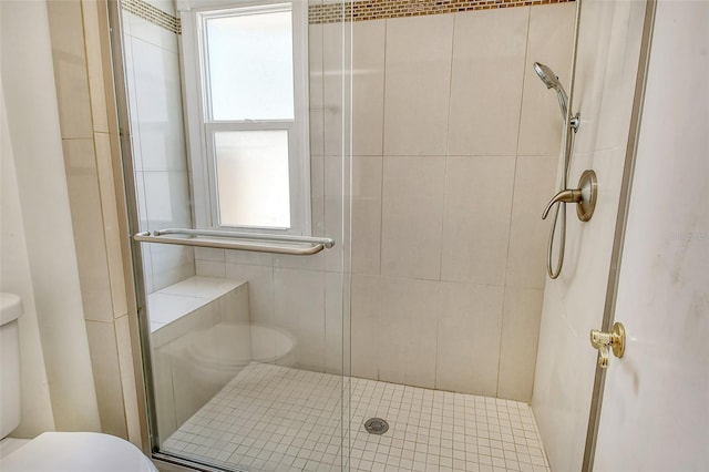 bathroom featuring a shower with door and toilet