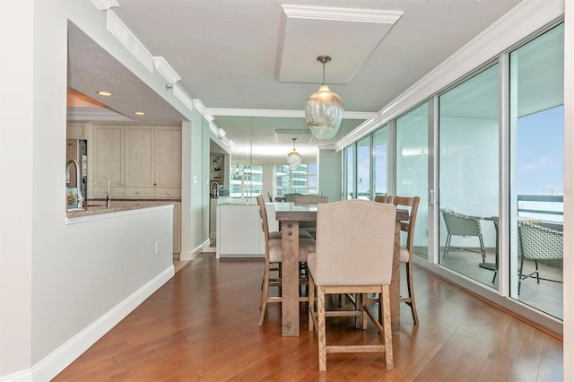 dining room with dark wood-type flooring, ornamental molding, and sink