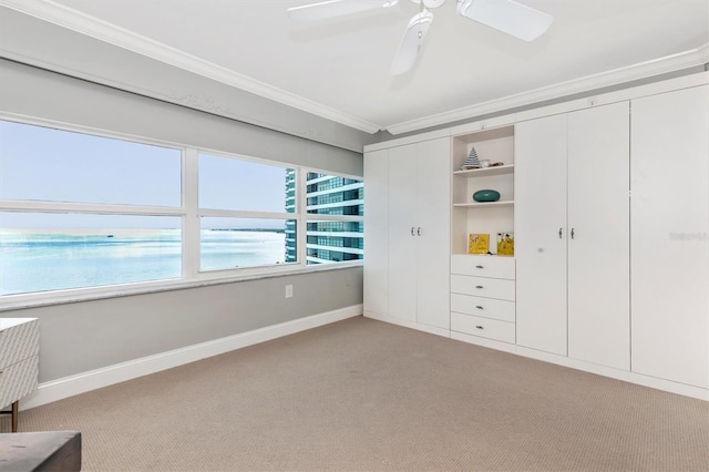 unfurnished bedroom with a water view, light colored carpet, crown molding, and ceiling fan