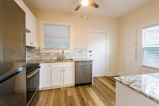 kitchen with appliances with stainless steel finishes, backsplash, sink, white cabinets, and light hardwood / wood-style floors