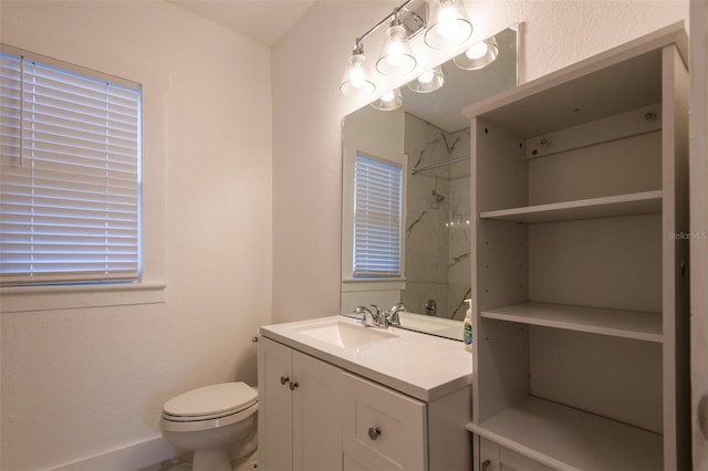 bathroom with toilet, vanity, and tiled shower