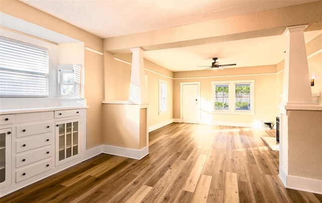 unfurnished living room with wood-type flooring, decorative columns, and ceiling fan