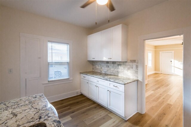 kitchen featuring white cabinets, light hardwood / wood-style floors, and light stone countertops