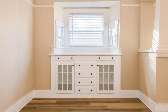 bar with white cabinetry, crown molding, and wood-type flooring