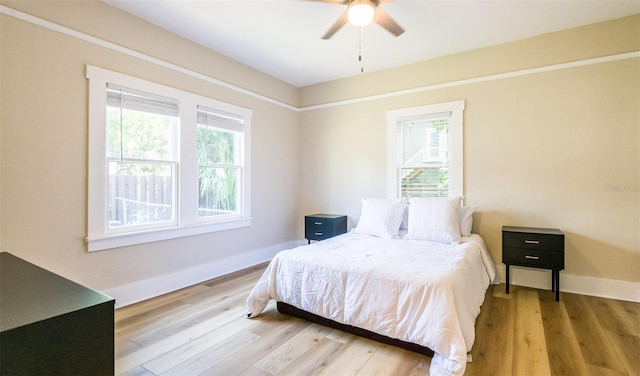 bedroom featuring multiple windows, ceiling fan, and light wood-type flooring