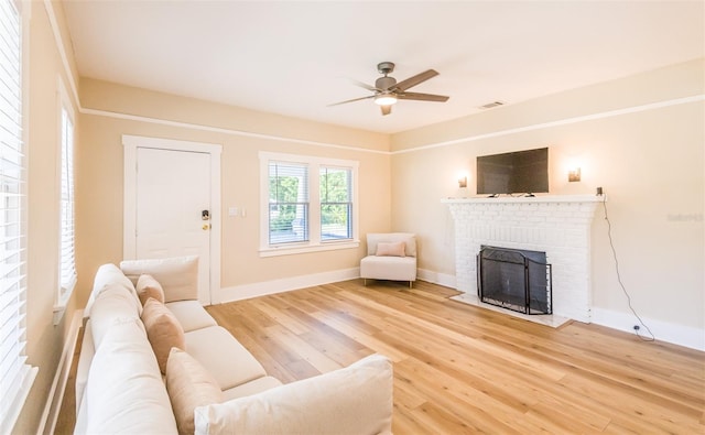 living room with ceiling fan, hardwood / wood-style floors, and a brick fireplace