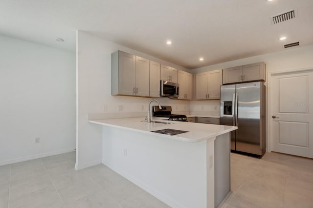 kitchen with sink, light tile patterned floors, kitchen peninsula, and appliances with stainless steel finishes