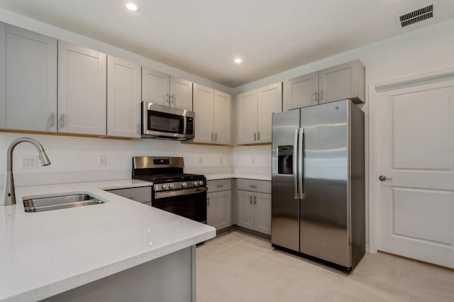 kitchen with gray cabinetry, appliances with stainless steel finishes, light tile patterned floors, and sink